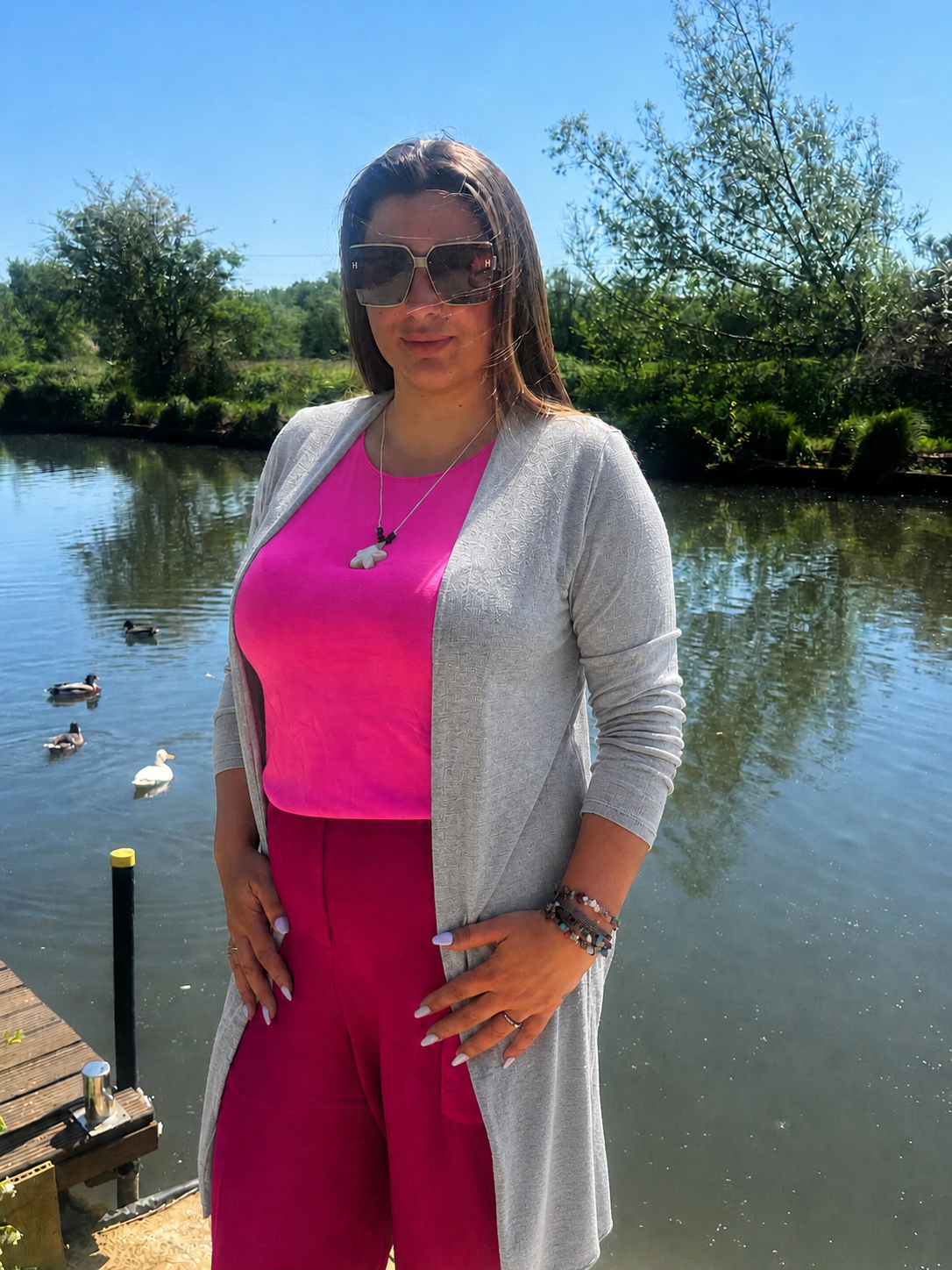 Woman wearing fuchsia pink vest, grey long line cardigan 