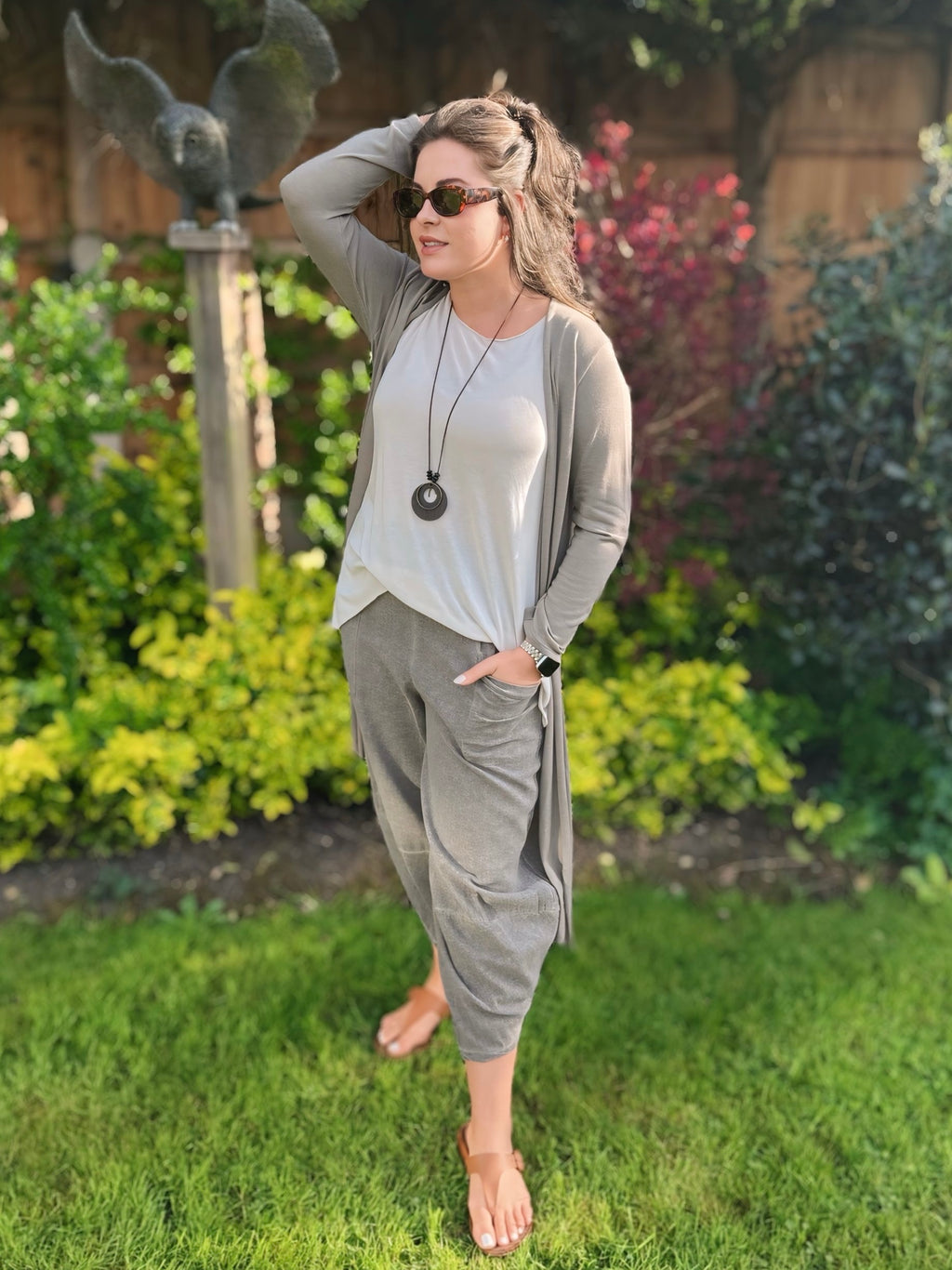 Woman in grey longline cardigan outfit standing in a garden