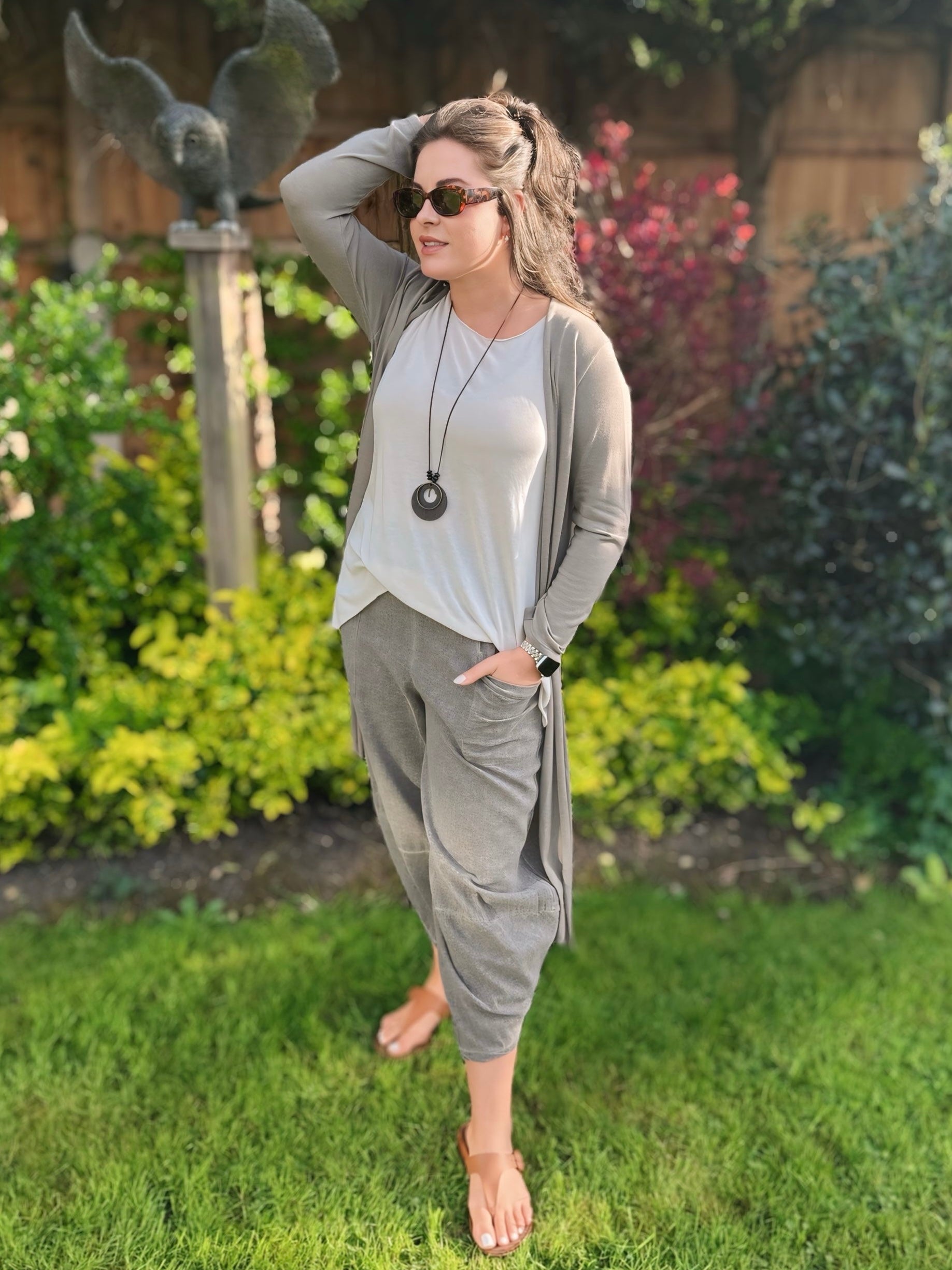 Woman in grey longline cardigan outfit standing in a garden